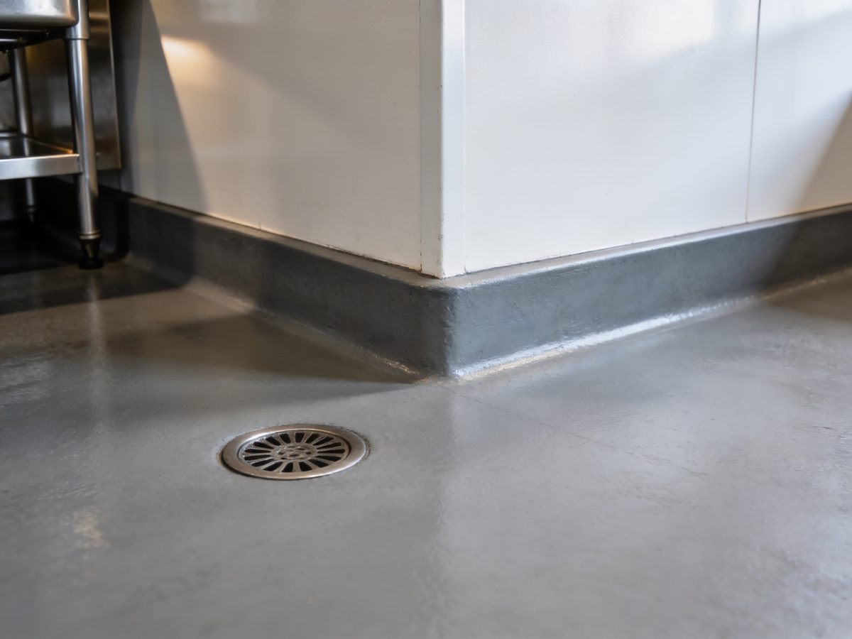 A commercial kitchen floor in seamless urethane cement with a coved base and a floor drain