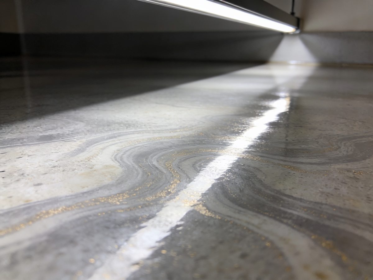 A metallic epoxy floor in limestone grey and pale gold pigments under a high-gloss topcoat